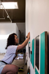 Hannah Marcotte makes reference marks at she measures to install her piece. Photo by Christy Marshall