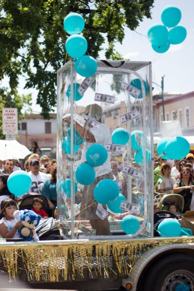 A local credit union’s float included a man inside a plastic box along with balloons and fake money.