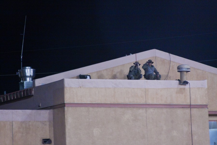 Two snipers survey the field at dusk from on top of Fire Station 1. Photo by Tim Kassiotis