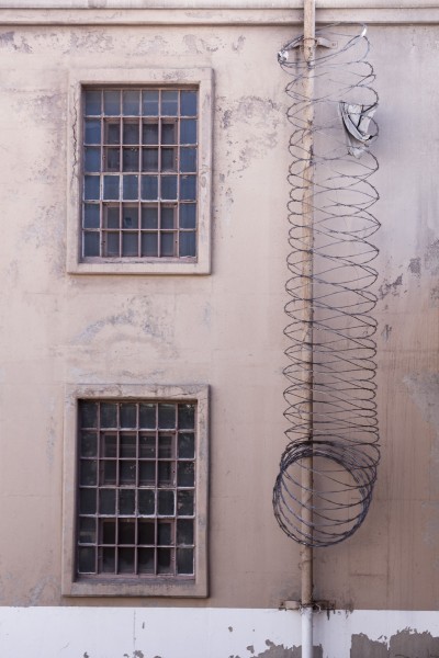 Concertina (razor) wire secures climbable lengths of pipe.