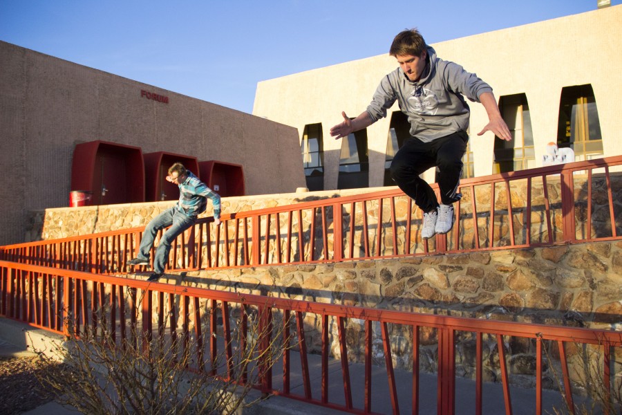 Gallegos and Stahlein jump over the railings outside the Fogelson Library.