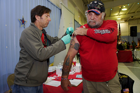 From left, Veterans Affairs RN Jeffrey Gittelman gives Army Veteran Boomer Montgomery a flu shot during the Santa Fe Veterans Stand down on Friday October 24, 2014. Photo by Luke E. Montavon/The Jackalope