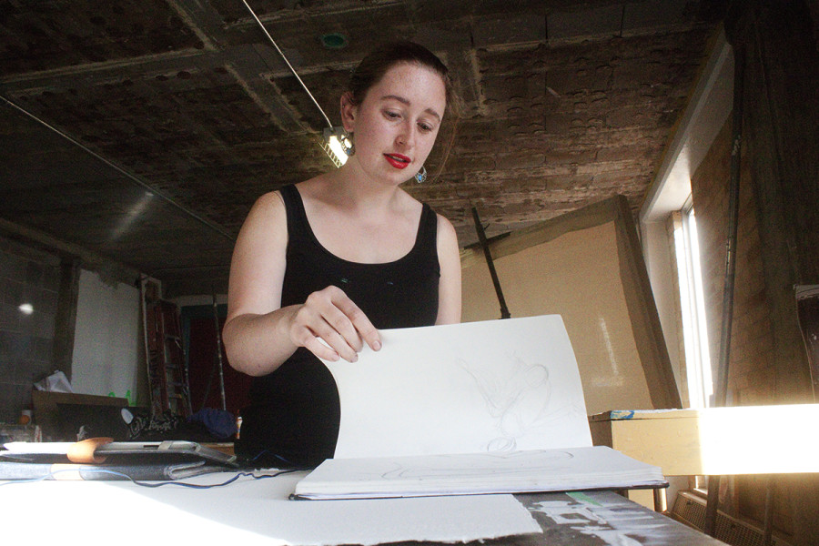 Hannah Gardner flips through her sketchbook in Alexis Hall. Photo by Andrew Koss