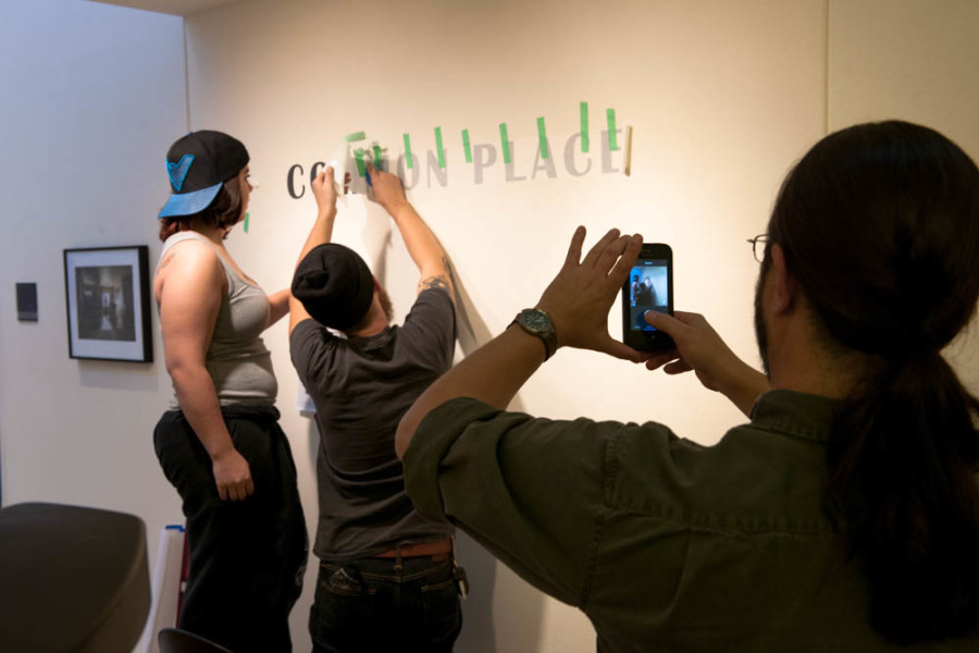 BFA students Samantha Podio and Brad Trone apply the vinyl lettering to their exhibition. Photo by Forrest Soper.