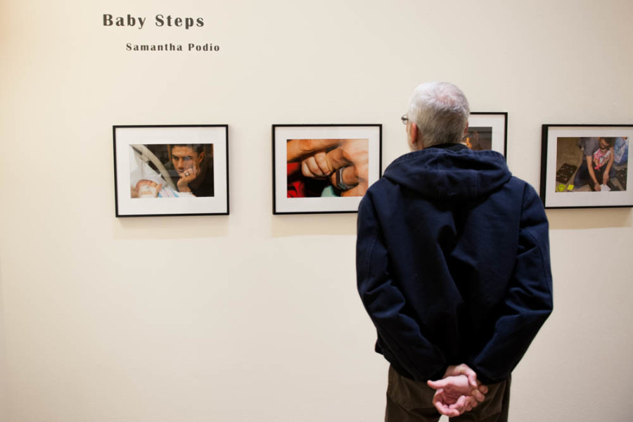 A gallery patron views images by Samantha Podio documenting the father’s role in the first year of a child’s life. Photo by Forrest Soper.