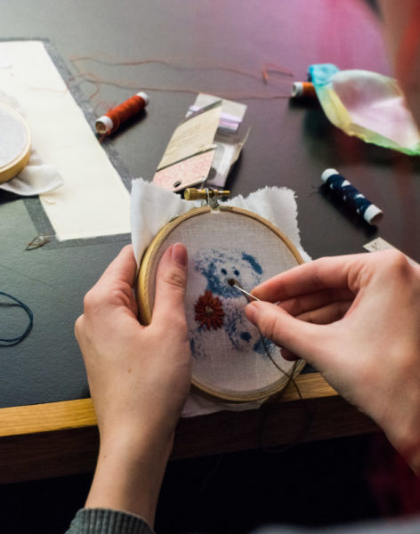 Christina Marshall delicately sews her cyanotype teddy. Photo by Sasha Hill