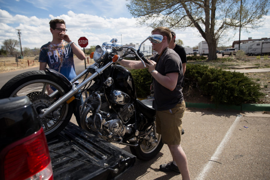 Aiden Willink and Derek Conkins help Ambrose Taylor unload his motorcycle out of a truck onto campus. Photo by Jason Stilgebouer