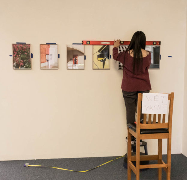 Jenn Carrillo makes sure her prints are leveled before she finishes hanging. Photo by Lexi Malone