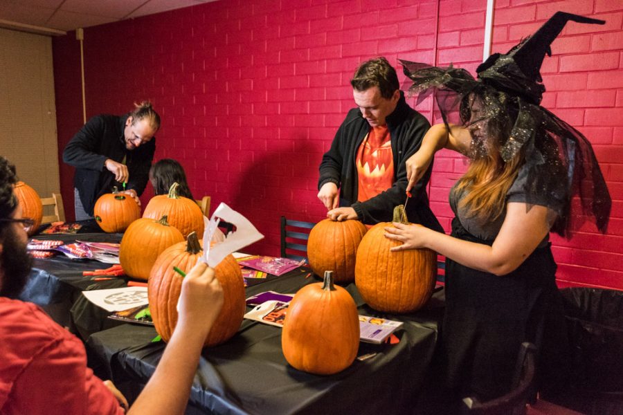 Students gather around the carving table as they begin to open up pumpkins. Photo by Sasha HIll