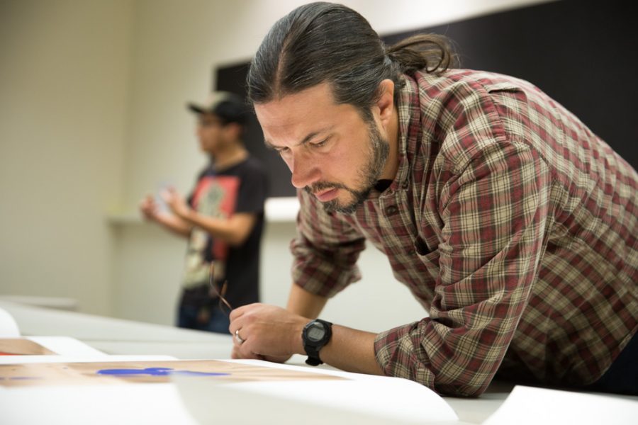 Photography teacher Chris Nail gets a closer look at Matthew Anderson’s thesis in detail during the Santa Fe University of Art and Design Photography Department salon. Photo by Jason Stilgebouer