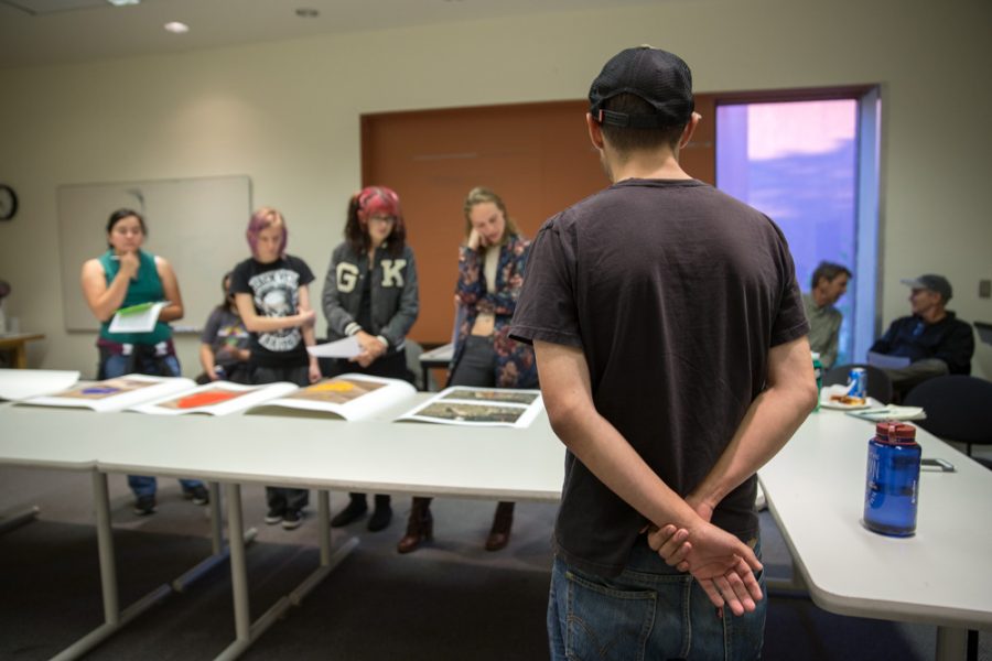 Matthew Anderson stands patiently as photography students review his work at the Santa Fe University of Art and Design Photography Department salon. Photo by Jason Stilgebouer